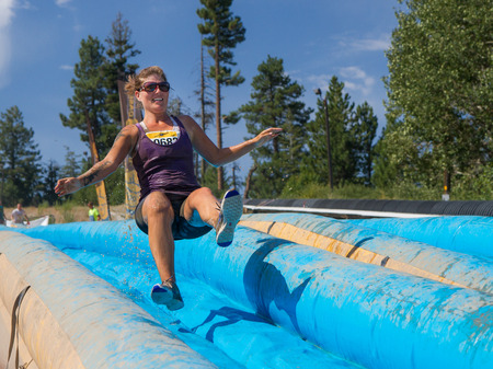 BOISE, IDAHO/USA - AUGUST 11: Runner 9682 jumps on the slide on her way to the finish line at the The Dirty Dash in Boise, Idaho on August 11, 2013 のeditorial素材