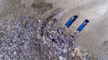 dumping of trash in a landfill by two trucksの写真素材