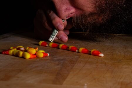 Bearded man trying to snort up the treat candy corn during fall right before halloweenの写真素材