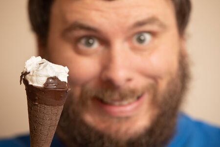 Man smiling in the background of a partially eaten ice cream coneの写真素材