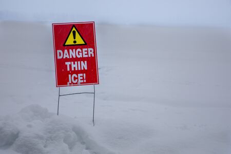 thin ice warning near a frozen lakeの写真素材