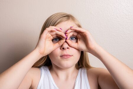 Young girl pretending to look through binocularsの写真素材