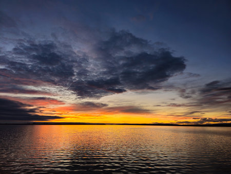 a sunset over a body of water with a cloudy skyの写真素材