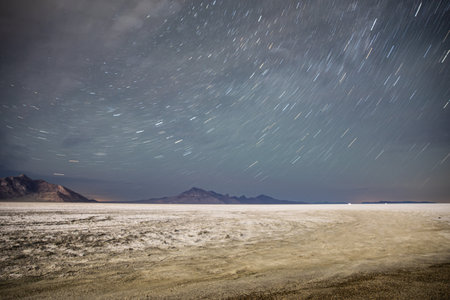 Starry Night Sky Over Vast Desert Landscapeの写真素材