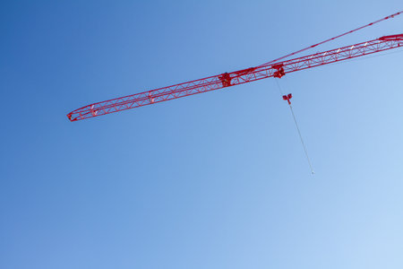 A crane is suspended in the air, with a red cable attached to itの写真素材