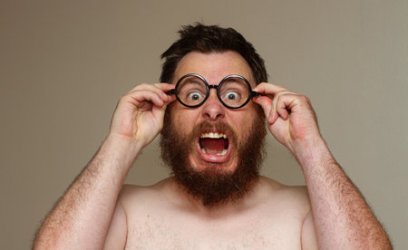 A man with glasses and a beard is wearing a shirtless and has his mouth openの写真素材