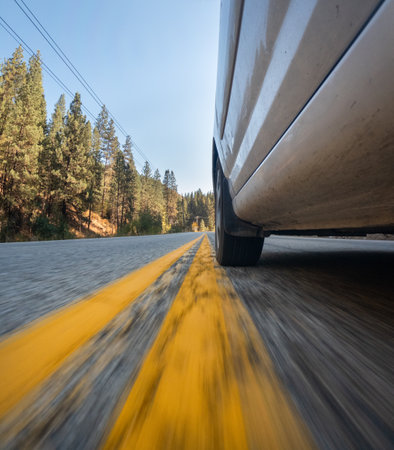 A car is driving down a road with yellow linesの写真素材