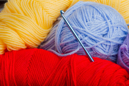 A blue crochet hook is sitting on top of a pile of yarnの写真素材