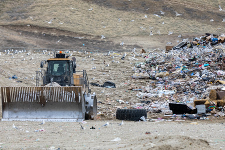 A large dump truck is driving through a pile of trashの写真素材