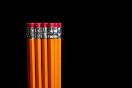A row of pencils with red erasers on top of a black backgroundの写真素材