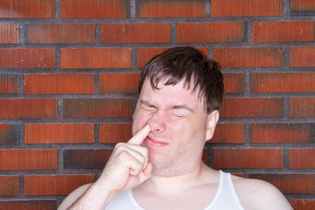 A man with a beard and a white tank top is making a faceの写真素材