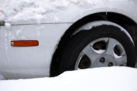 A car with snow on it and the back tire is frozenの写真素材