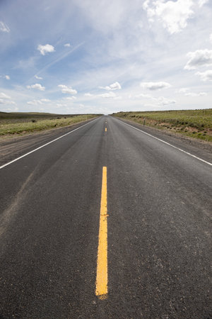 A long, empty road with a yellow line down the middleの写真素材