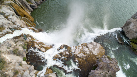 A waterfall is seen from above, with the water spraying into the airの写真素材