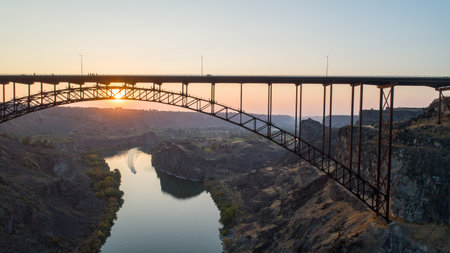 A bridge spans a river with a sunset in the backgroundの写真素材