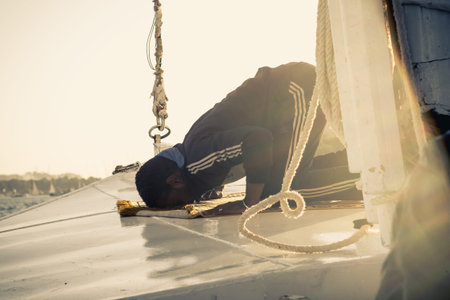 Black young man praying to Allah at the sunset on a boat