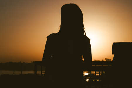 Woman silhouette with sunset backgroundの写真素材