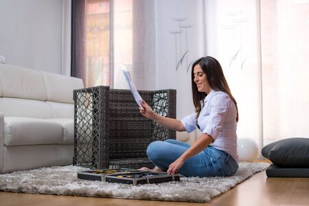 young woman assembling armchair furniture in home interiorの写真素材
