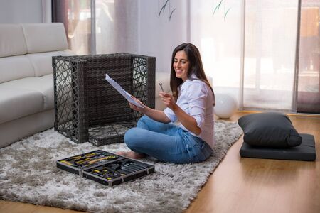 young woman assembling armchair furniture in home interiorの写真素材