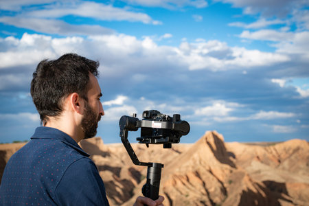 young filmmaker filming natural landscape in canyon with a large river and marshes