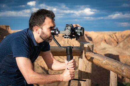 young filmmaker filming natural landscape in canyon with a large river and marshesの写真素材