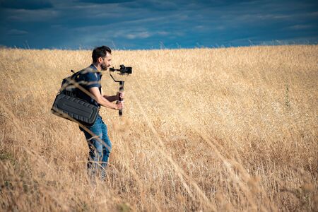 young filmmaker filming natural landscape in canyon with a large river and marshesの写真素材