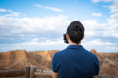 young filmmaker filming natural landscape in canyon with a large river and marshesの写真素材