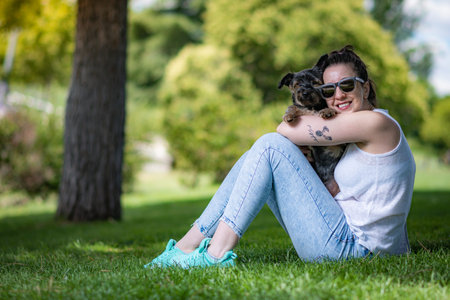 young woman with beautiful yorkshire posing and playing sympathetically in a garden with grass and...