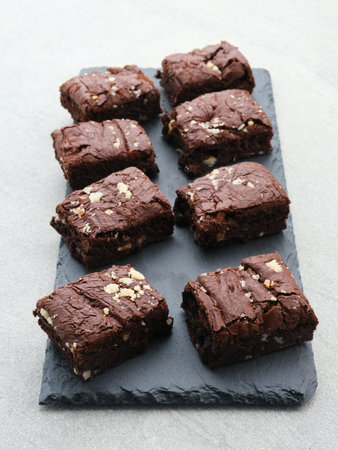 Homemade fudgy chocolate brownies on black board. Selective focus image and blurred background.の写真素材
