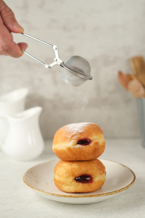 Bomboloni with strawberry jam filling. Served on a white plate on the table. Blurred background and...