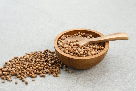 Dried coriander seeds, Coriandrum sativum or Ketumbar served on small wooden bowl. Selective focus image.の写真素材