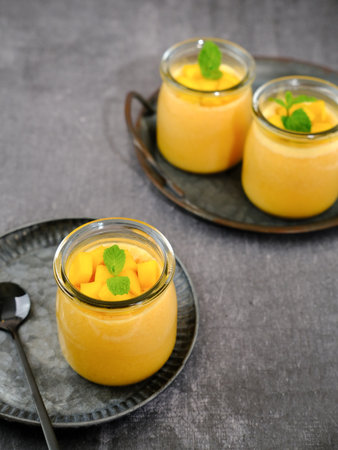 Mango pudding topped with mango chunks and mint leaf garnish. Served in a jar. Very fresh and healthy.の写真素材