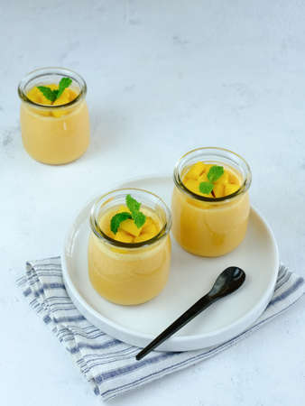 Mango pudding topped with mango chunks and mint leaf garnish. Served in a jar. Very fresh and healthy.の写真素材
