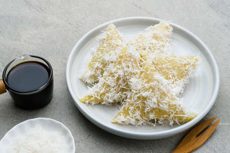 Lupis or Lopis, a traditional Indonesian food made from sticky rice and wrapped in banana leaves. Served with grated coconut and liquid brown sugar. Selective focus image.の写真素材