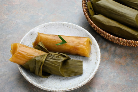 Lemet Singkong or Utri or Ketimus is a traditional cake that uses processed grated cassava inside which is given brown sugar wrapped in banana leaves and steamed. Served in white plate.の写真素材