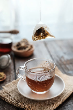 A cup of tea with lemon and honey for breakfast. Served in glass on wooden table. Selective focus image, blurred background.の写真素材