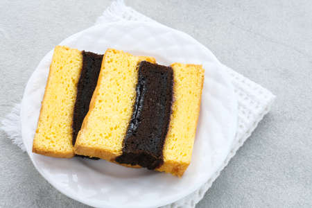 Spiku or Lapis Surabaya or Surabaya Layer Cake is a three-layer sponge cake with strawberry jam in between. Served in white plate, close up.の写真素材