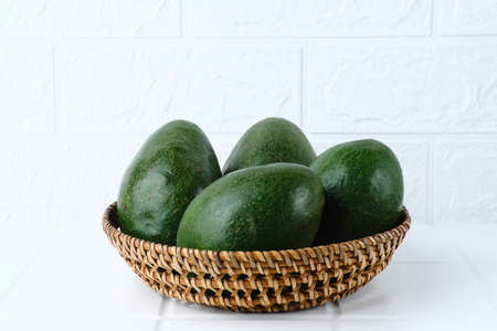 Alpukat or Avocado (Persea americana), ripe and fresh, served in rattan basket on white background, close up and copy space.の写真素材