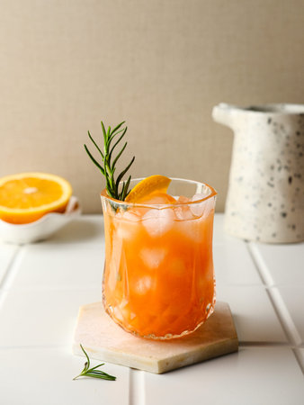 Orange juice in glass with rosemary, fresh fruits on the table. Selective focus and blurred...