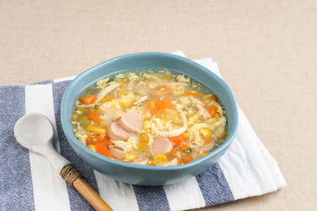 Corn cream soup with chicken, sausage, egg, carrots and cornstarch, savory and delicious. Served in bowl, copy space.の写真素材