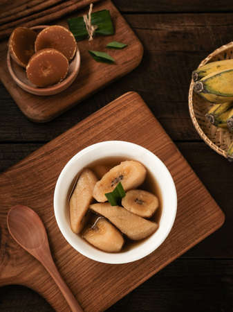 Setup Pisang is traditional dessert made of banana, palm sugar boiled with cinnamon, pandan leaves and cloves. Selective focus image. Served in white bowl on grey background.の写真素材