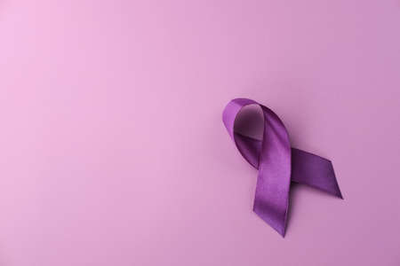 Purple ribbon as symbol of World Cancer Day over purple color background, copy space.の写真素材