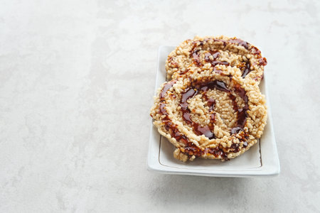 Rice crackers (intip madu or rengginang) with brown sugar on white background. Savory, sweet and...