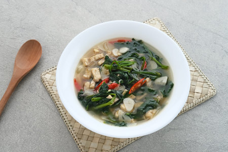 Tumis or Ca Kangkung Terasi with Tempeh, is one of Indonesian food. Served on white bowl on grey...