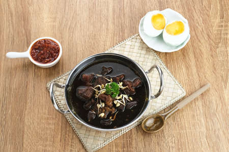 Rawon, Indonesian Traditional beef black soup. Served on a bowl with mung bean sprouts, chilli paste and salted eggの写真素材