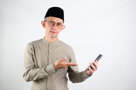 Portrait of Asian Moslem Man holding mobile phone, showing applicationの写真素材
