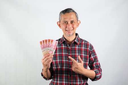 Portrait of Asian Man with casual shirt looking happy with holding lots of money in handの写真素材