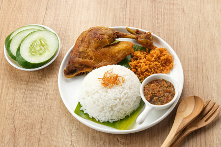 Bebek Goreng Kremes, served with chili sauce (sambal) and cucumber. Indonesian foodの写真素材