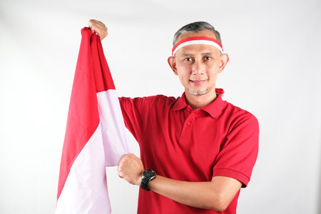 Portrait of Asian Man holding red and white Indonesia flag attribute. Independence day concept.の写真素材