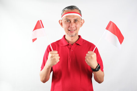 Portrait of Asian Man holding red and white Indonesia flag attribute. Independence day concept.の写真素材